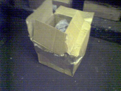 1994 Ford Bronco - A damaged cardboard box sits on a dark surface, obscuring its contents.
