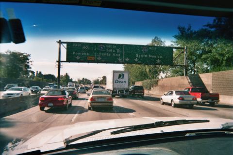 1990 Ford Bronco - View through a car windshield of congested multi-lane freeway traffic beneath green overhead exit signs for Pomona, Santa Ana and Santa Mon…