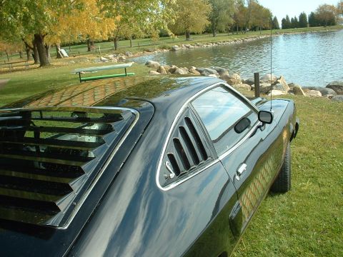 1978 Ford Mustang II - Rear quarter view of a black 1978 Ford Mustang II parked next to a lake during autumn.