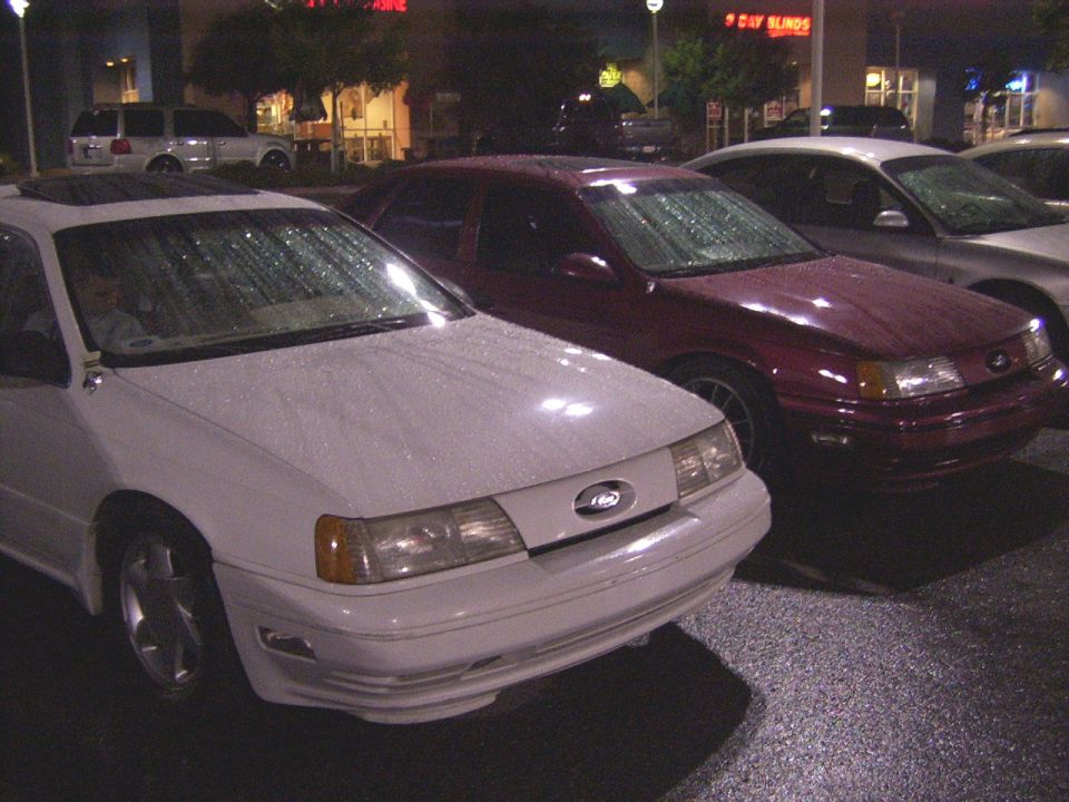 White sedan with a sunroof, front view, in the rain