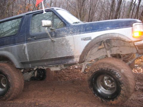 1995 Ford Bronco - Muddy 1995 Ford Bronco navigating rough terrain with a red flag visible.