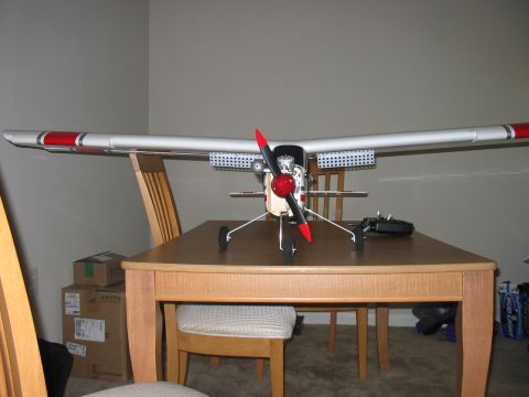 1988 Ford Bronco - A model airplane with a red propeller is displayed on a wooden table, with chairs and boxes in the background.