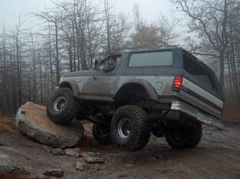 1995 Ford Bronco - This lifted Ford Bronco navigates a rocky trail in a wooded area.