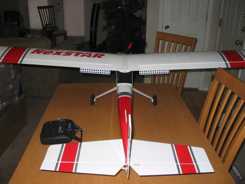 1988 Ford Bronco - A radio-controlled airplane, labeled 'NEXSTAR', rests on a table next to its remote control.