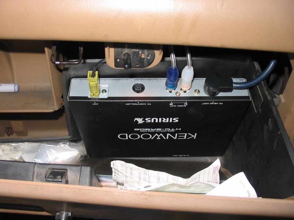 Kenwood Sirius car stereo unit with cables inside a vehicle's glove compartment