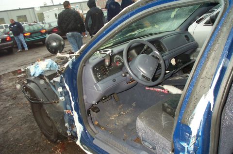 1991 Ford LTD Crown Victoria - The interior of a blue sedan shows significant damage to the front passenger side, with the fender detached.