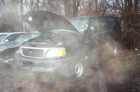 1991 Ford LTD Crown Victoria - A black Ford Expedition sits in a wooded area with its hood open, next to another vehicle.