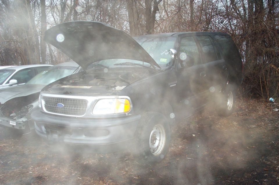 Black Ford Expedition with hood open, parked next to another damaged car