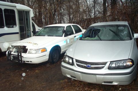 1991 Ford LTD Crown Victoria - A silver Chevrolet Impala sits next to a white police car in an outdoor lot.