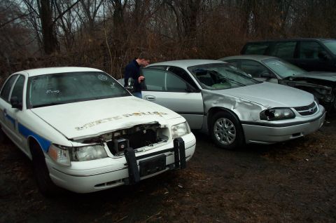 1991 Ford LTD Crown Victoria - White police car with damage to the front end and a blue stripe along the side. Text on the hood reads "STATE POLICE".