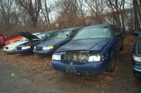 1991 Ford LTD Crown Victoria - Multiple Ford Crown Victorias are parked in a lot, some with hoods open and missing parts.
