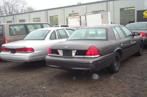 1991 Ford LTD Crown Victoria - Rear view of a dark grey sedan, likely a 1998 Ford Crown Victoria, parked next to a silver sedan.