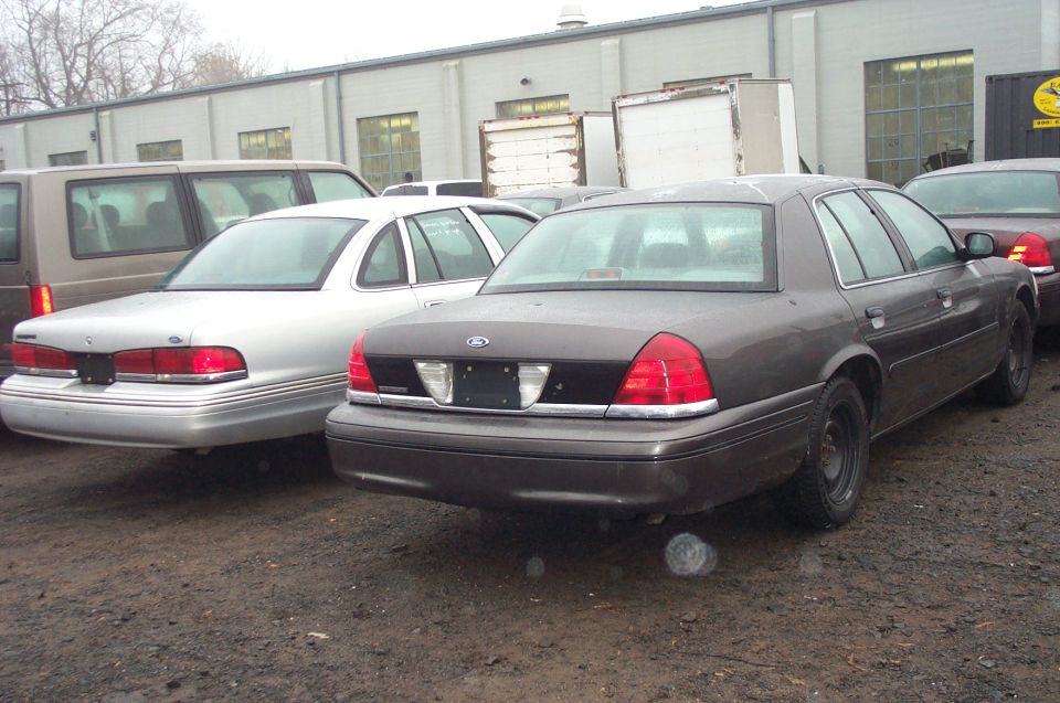 Dark grey sedan, rear view. Appears to be a 1998 Ford Crown Victoria