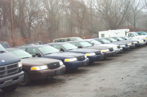 1991 Ford LTD Crown Victoria - A row of Ford Crown Victoria police cars are parked outside on a cloudy day.