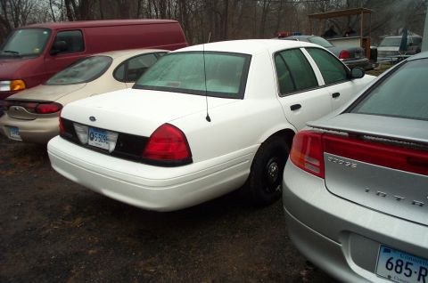 1991 Ford LTD Crown Victoria - Rear view of a white sedan parked between other vehicles.