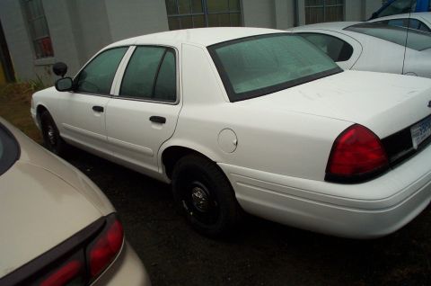 1991 Ford LTD Crown Victoria - A white sedan with tinted windows is parked outdoors next to another vehicle.