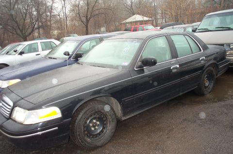 1991 Ford LTD Crown Victoria - A black Ford Crown Victoria sedan is parked in a lot with other vehicles.