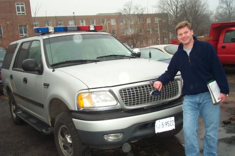 1991 Ford LTD Crown Victoria - A man stands next to a silver Ford Expedition equipped with a light bar, with a red truck visible in the background.