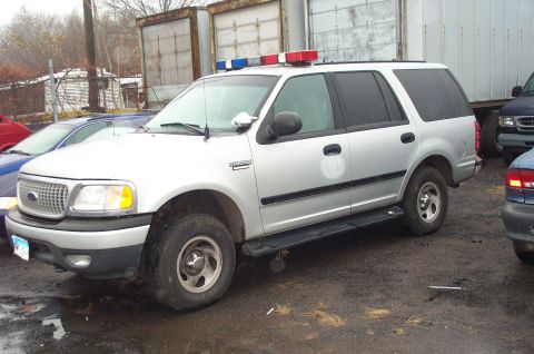 1991 Ford LTD Crown Victoria - Silver SUV with a light bar on the roof is parked next to other vehicles.