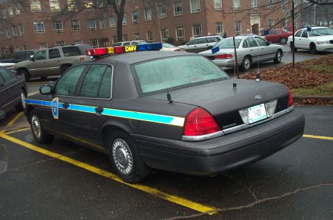 1991 Ford LTD Crown Victoria - Police car with light bar and distinctive stripe parked in a lot.