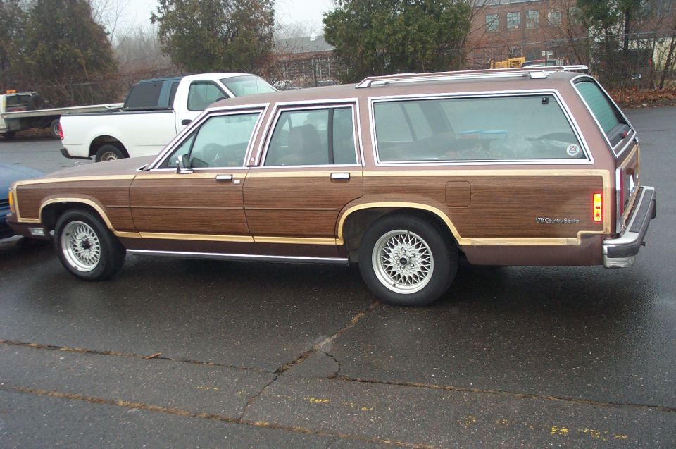 Wood-paneled station wagon, brown, side view, with wire wheels and roof rack