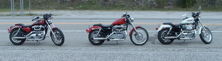 1995 Mercury Grand Marquis - Three motorcycles are lined up on the shoulder of a road.