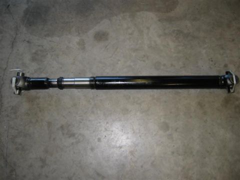 1994 Ford Bronco - A driveshaft is shown lying on a concrete surface. The part is black and has metal components at each end.