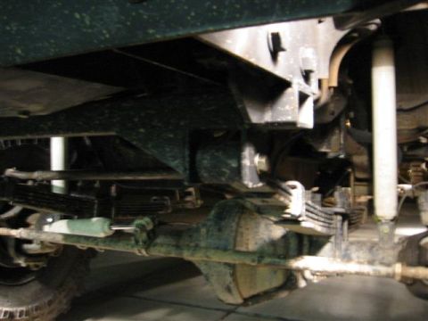 1994 Ford Bronco - Close-up of vehicle undercarriage with leaf spring suspension and shock absorbers.