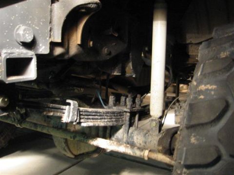 1994 Ford Bronco - The underside of a vehicle shows its rear suspension components, including leaf springs and a shock absorber.