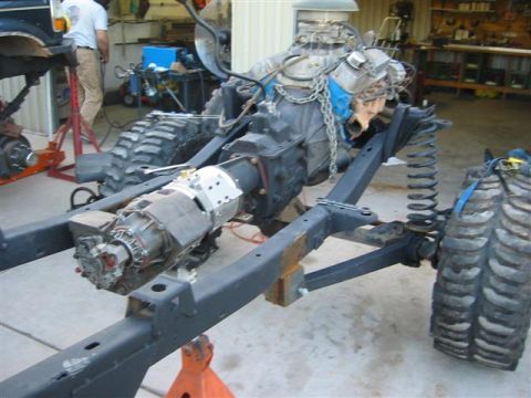 1994 Ford Bronco - The chassis of a vehicle is shown with its engine and transmission assembly, supported by jack stands in a workshop.