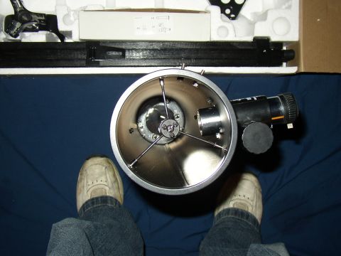 1987 Volkswagen Golf - Interior view of a telescope, showing its optical components and tripod mount. The item is in its packaging, with a person's feet visible i…
