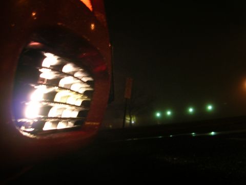 1992 Nissan 240SX - Car grille illuminated at night, with distant lights visible through fog.