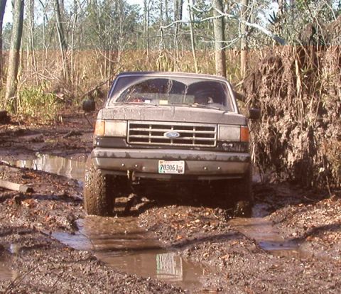 1988 Ford Bronco - This 1988 Ford Bronco navigates a muddy trail surrounded by trees.