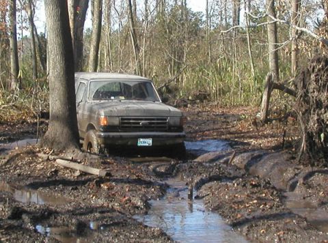 1988 Ford Bronco - Ford Bronco navigating a muddy trail in the woods.