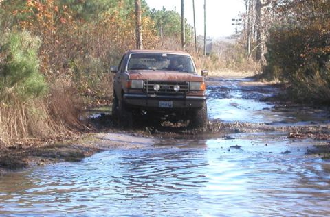 1988 Ford Bronco - Ford Bronco navigating a muddy trail with water obstacles.