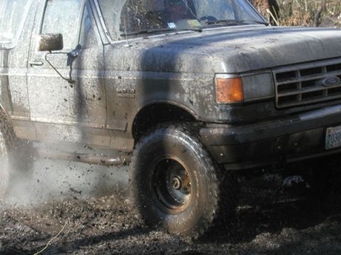 1988 Ford Bronco - This 1988 Ford Bronco is covered in mud as it drives through a muddy terrain.