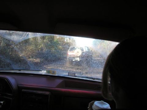 1988 Ford Bronco - Two vehicles travel down a muddy, tree-lined path, seen through a dirty windshield.