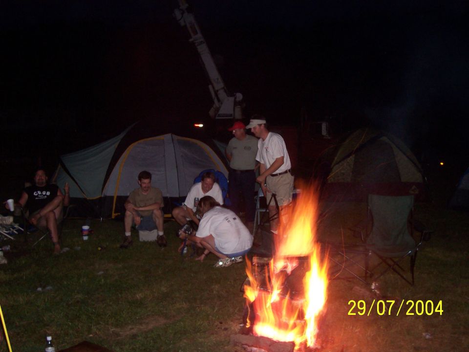 Campfire scene at night with tents and people gathered