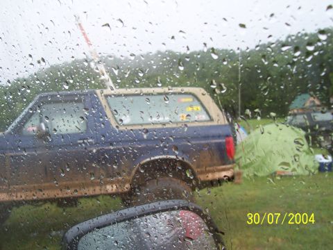 1979 Ford F-150 - A muddy Ford Bronco is parked next to a tent on a rainy day in 2004.