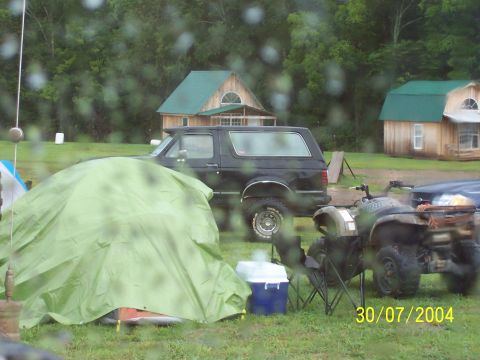 1979 Ford F-150 - A black SUV is parked near a campsite with a tent and ATVs visible.