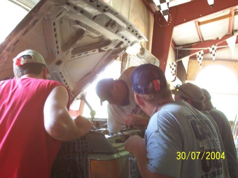 1979 Ford F-150 - Several individuals are gathered around the open hood of a vehicle, appearing to work on the engine.