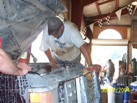 1979 Ford F-150 - Mechanics work on the front end of a 1979 Ford F-150 inside a cluttered garage.