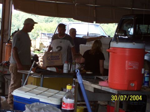 1979 Ford F-150 - Group of people in a workshop with a cooler and two trucks in the background. Date stamp reads 30/07/2004.