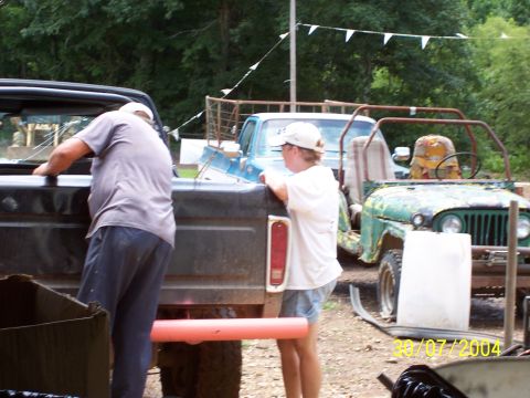 1979 Ford F-150 - Two people stand near the back of a pickup truck, with a green jeep visible in the background.