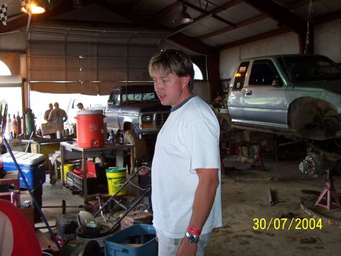 1979 Ford F-150 - A man stands in a garage with two trucks undergoing repairs.