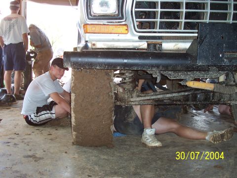 1979 Ford F-150 - Mechanics work on the undercarriage of a lifted 1979 Ford F-150 truck.