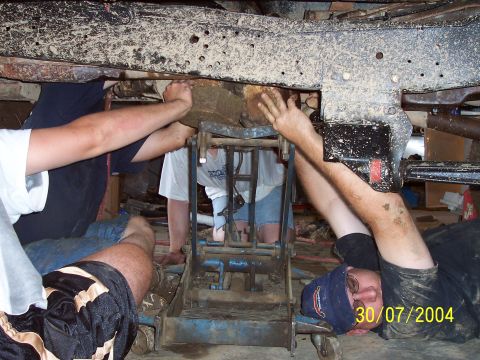 1979 Ford F-150 - Mechanics work on the underside of a vehicle, possibly performing repairs or modifications.