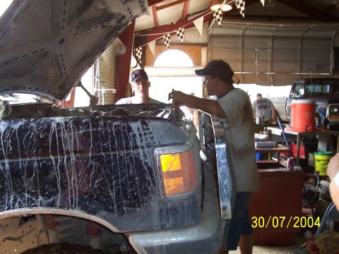 1979 Ford F-150 - Mechanics are working on a dark colored truck inside a garage. Another truck is parked in the background.