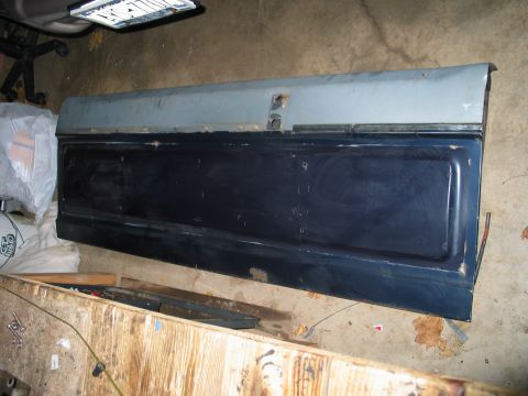 1995 Ford Bronco - A vehicle tailgate is shown lying on a concrete floor, possibly in a garage or workshop.