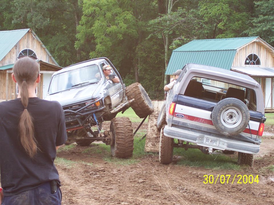 Two off-road trucks in mud, one with a spare tire on the back